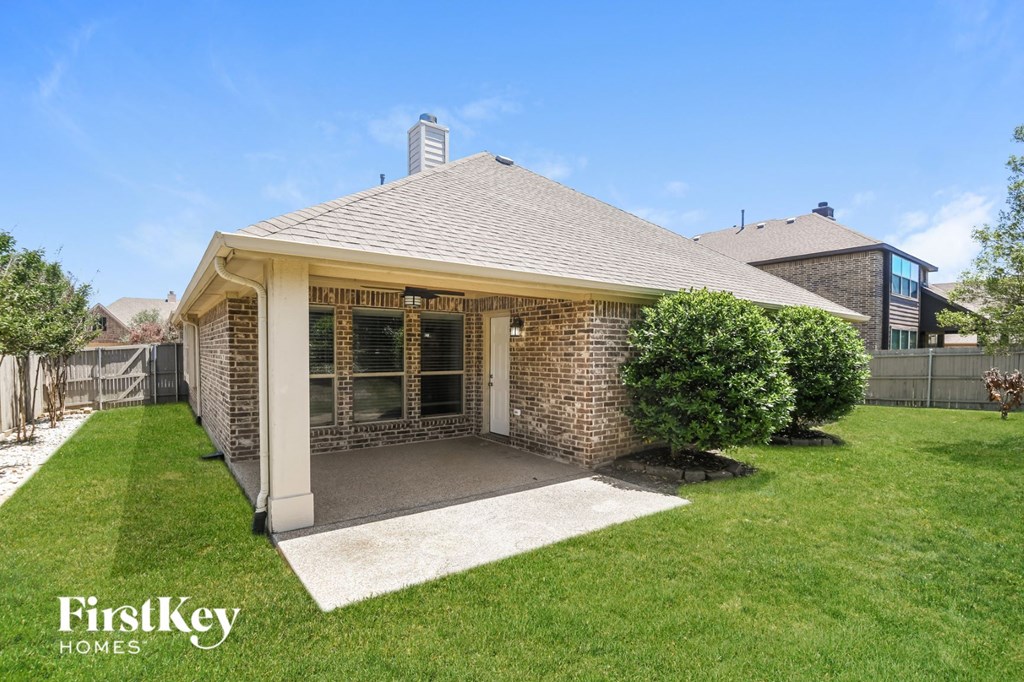 a patio in the backyard of a brick house
