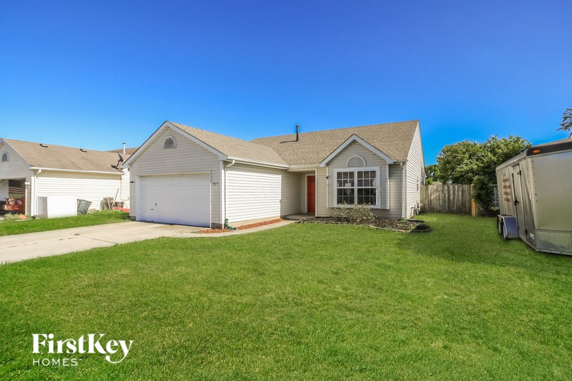 a small white house with a yard and a driveway