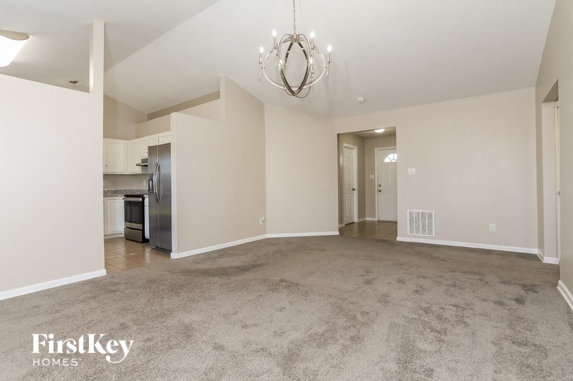 an empty living room and kitchen with a chandelier
