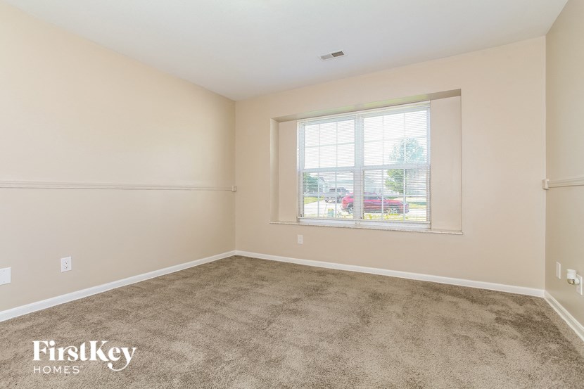 an empty living room with a window and carpet