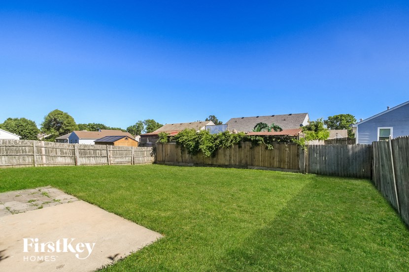 a backyard with a grass lawn and a wooden fence