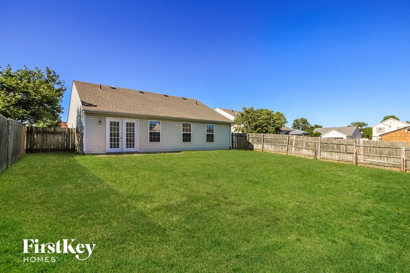 a backyard with a small white house and a fence