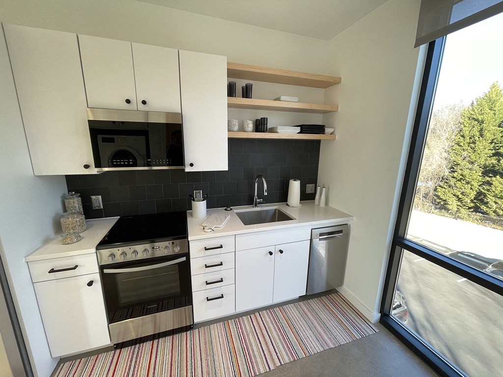 a small kitchen with white cabinets and a window