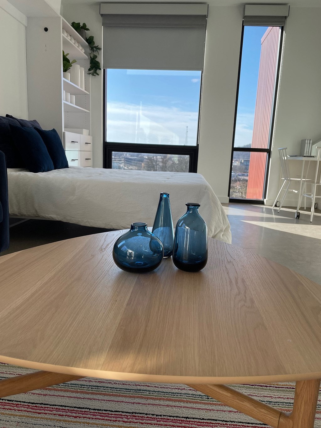 a coffee table with blue vases on it in a living room with a bed