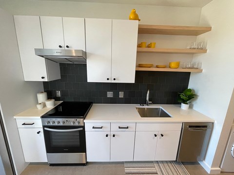 A modern kitchen with white cabinets and black countertops.