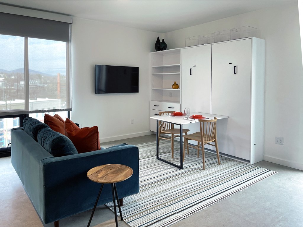 a living room and dining room with a blue couch and a table and chairs