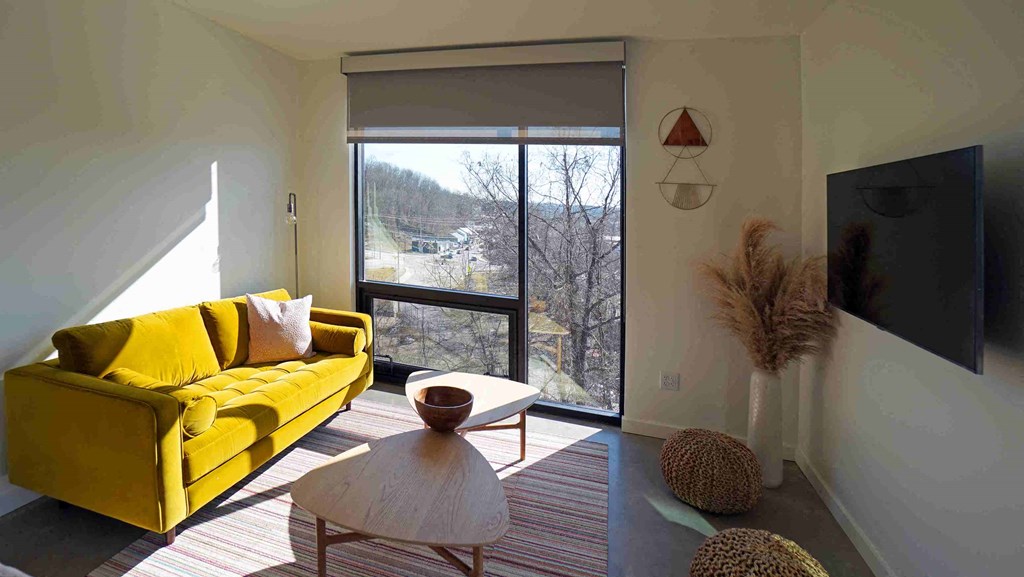 a living room with a yellow couch and a sliding glass door