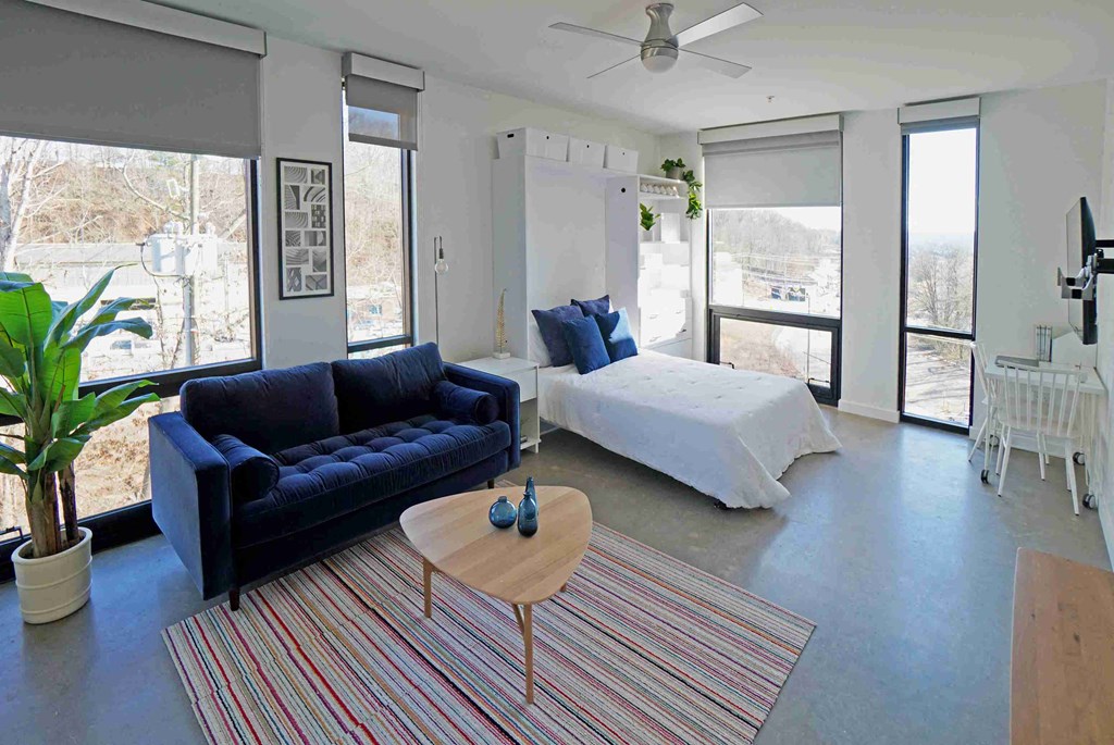 a living room with a couch and a table in front of a bed