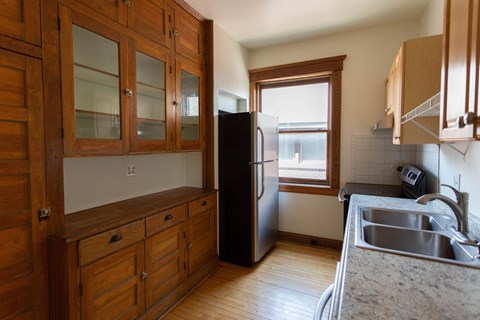 A kitchen with wooden cabinets and a black refrigerator.