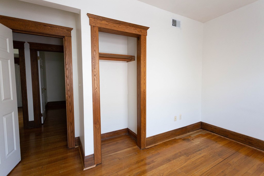 a room with wood floors and a door to a closet
