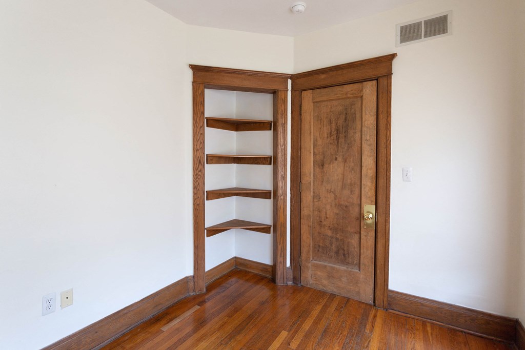 an empty room with a wooden door and a book shelf