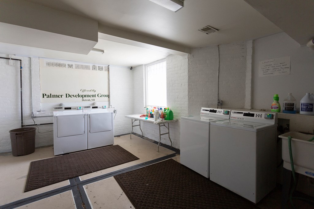 a laundry room with four washes and a table with bottles of laundry detergent