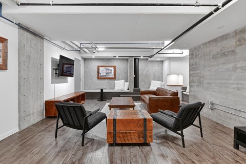 A modern living room with a wooden floor and black chairs.