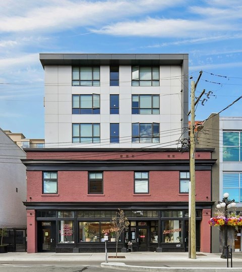 A modern building with a red brick base sits on a street corner.