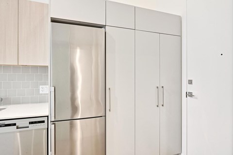A kitchen with a stainless steel refrigerator and white cabinets.