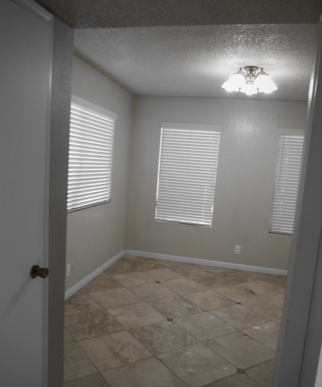 a small room with a tiled floor and white walls and a window with white