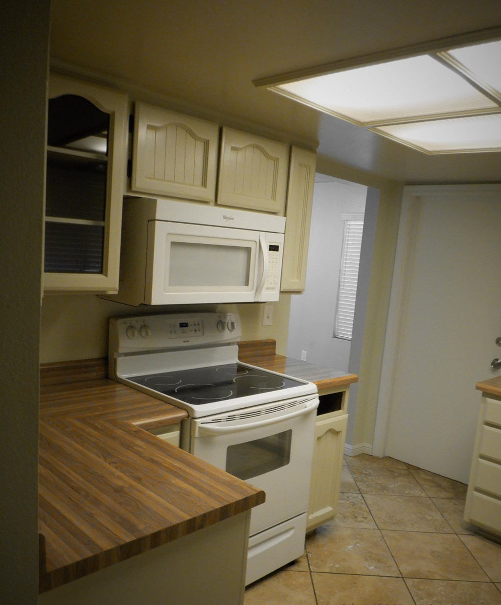 an empty kitchen with white appliances and white cabinets
