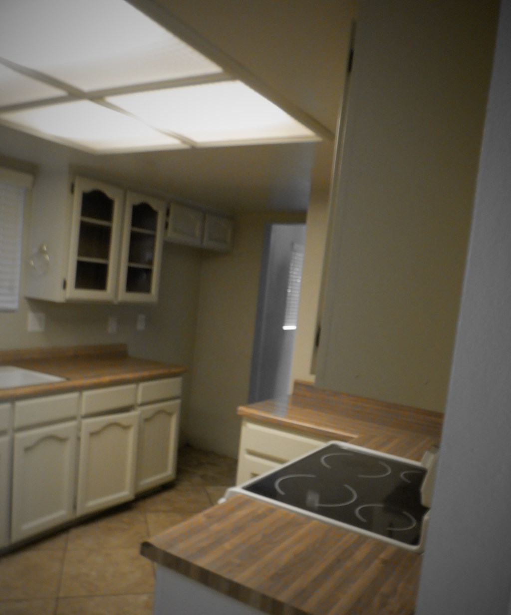 an empty kitchen with white cabinets and a stove