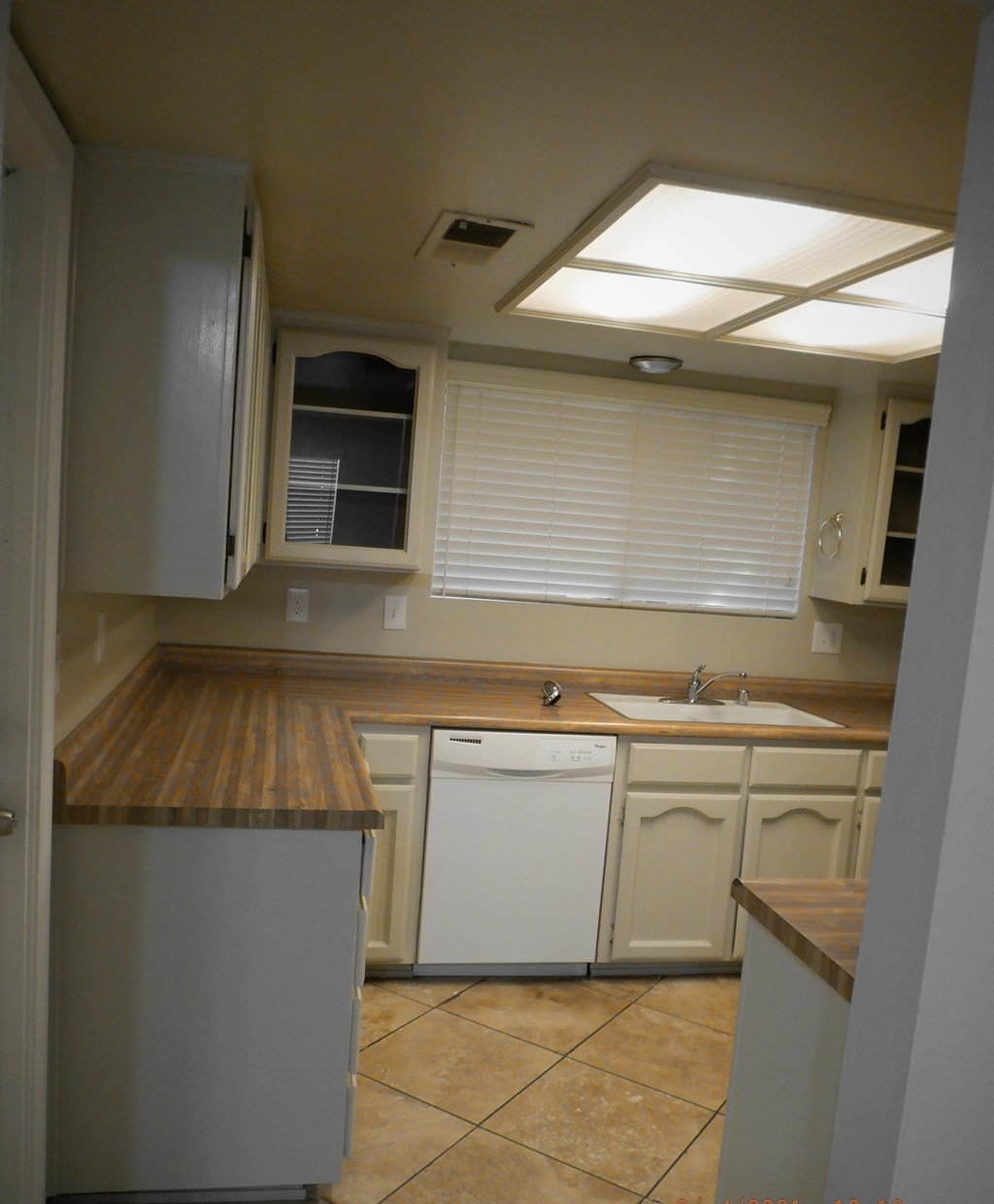an empty kitchen with white cabinets and a white dishwasher