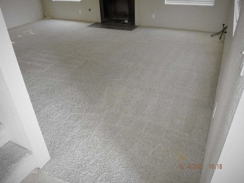 a carpeted living room with white carpet and a fireplace