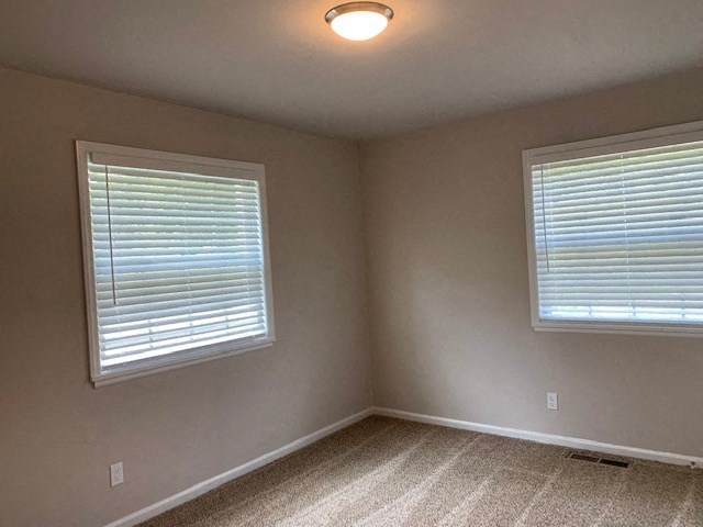 an empty room with two windows and a ceiling light