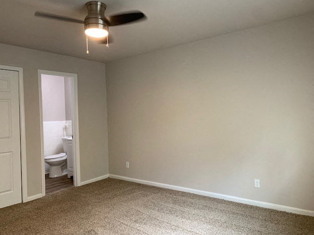 an empty living room with a ceiling fan and a toilet