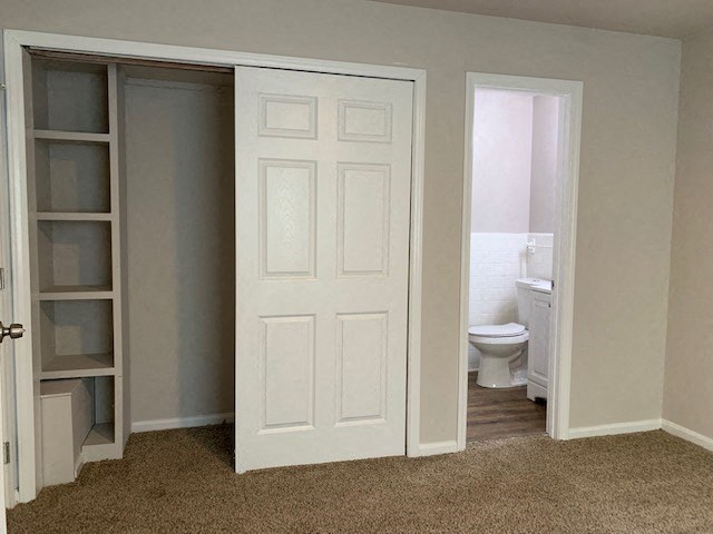 a bathroom with a closet door and a toilet