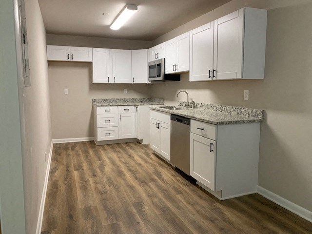 an empty kitchen with white cabinets and a sink