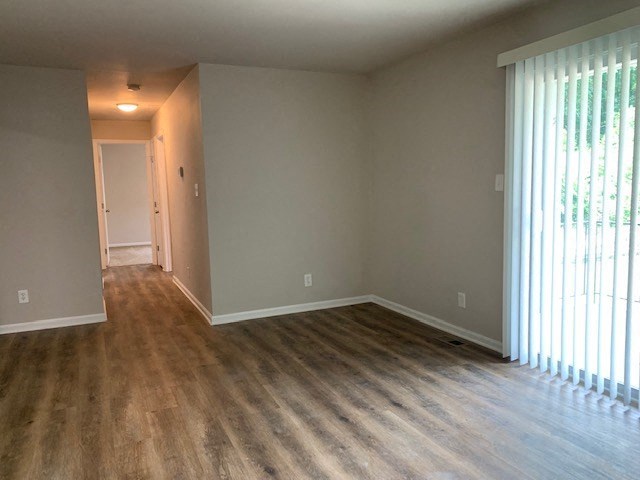 an empty living room with a large window and wooden floors