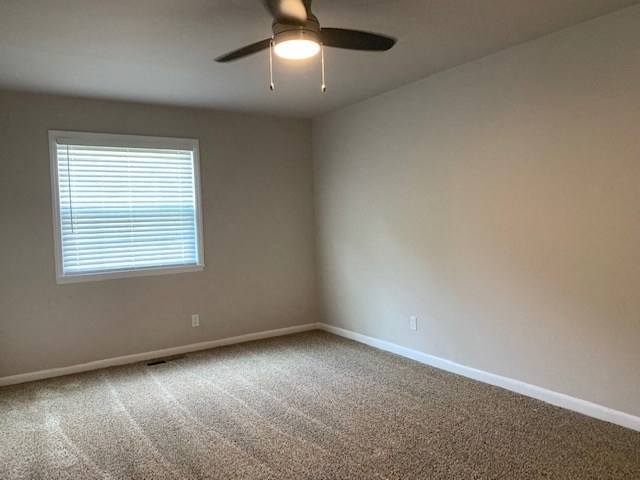an empty room with a ceiling fan and a window