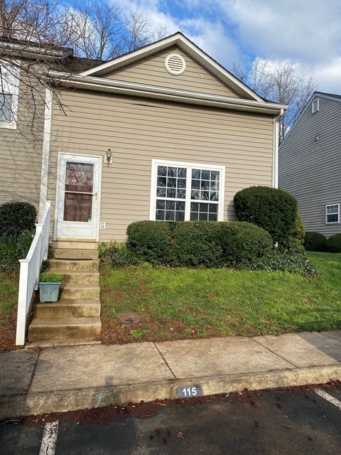 a tan house with a white door and steps to a sidewalk