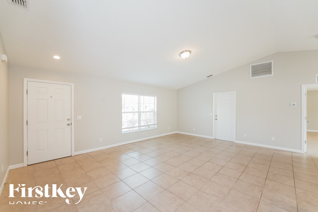 A spacious empty room with a tiled floor and white walls.