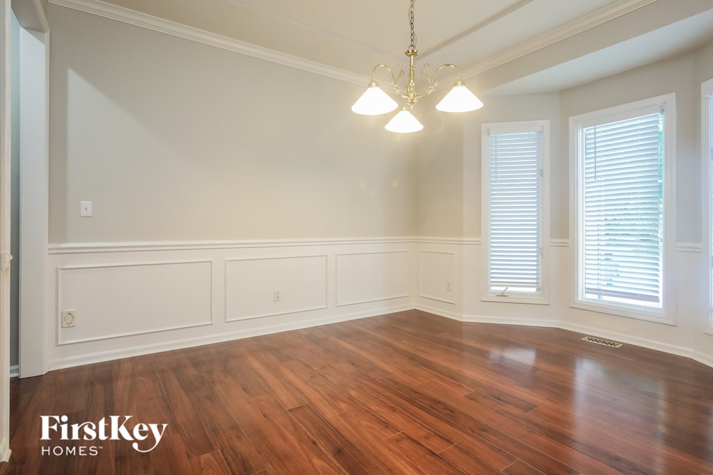 a dining room with wood floors and white walls and a chandelier