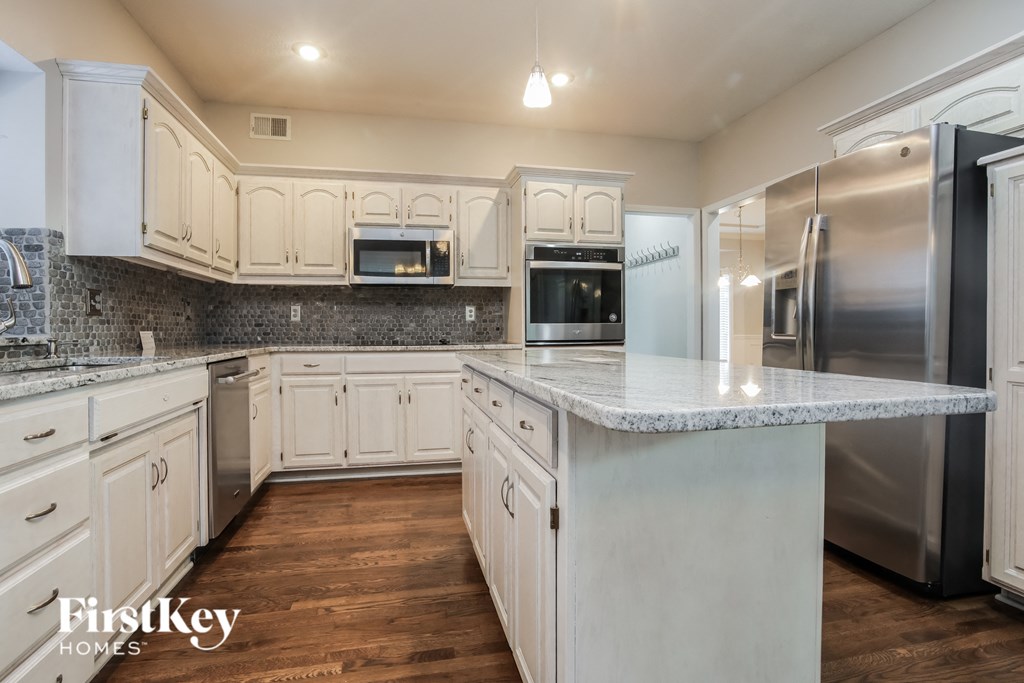 a white kitchen with stainless steel appliances and marble counter tops