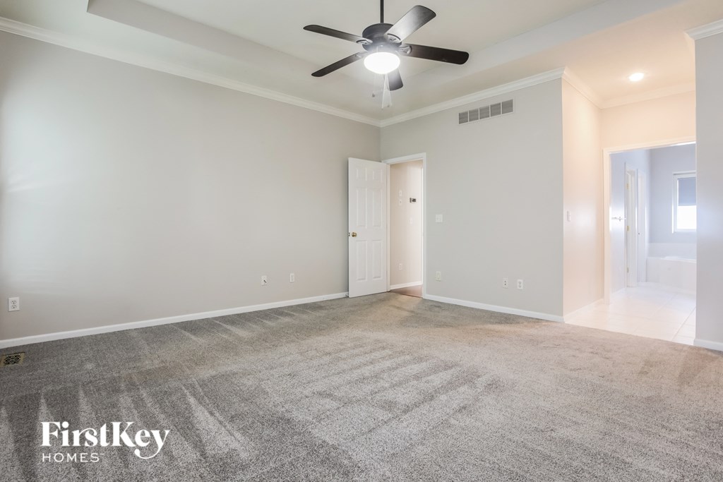 a empty living room with a ceiling fan and carpeting