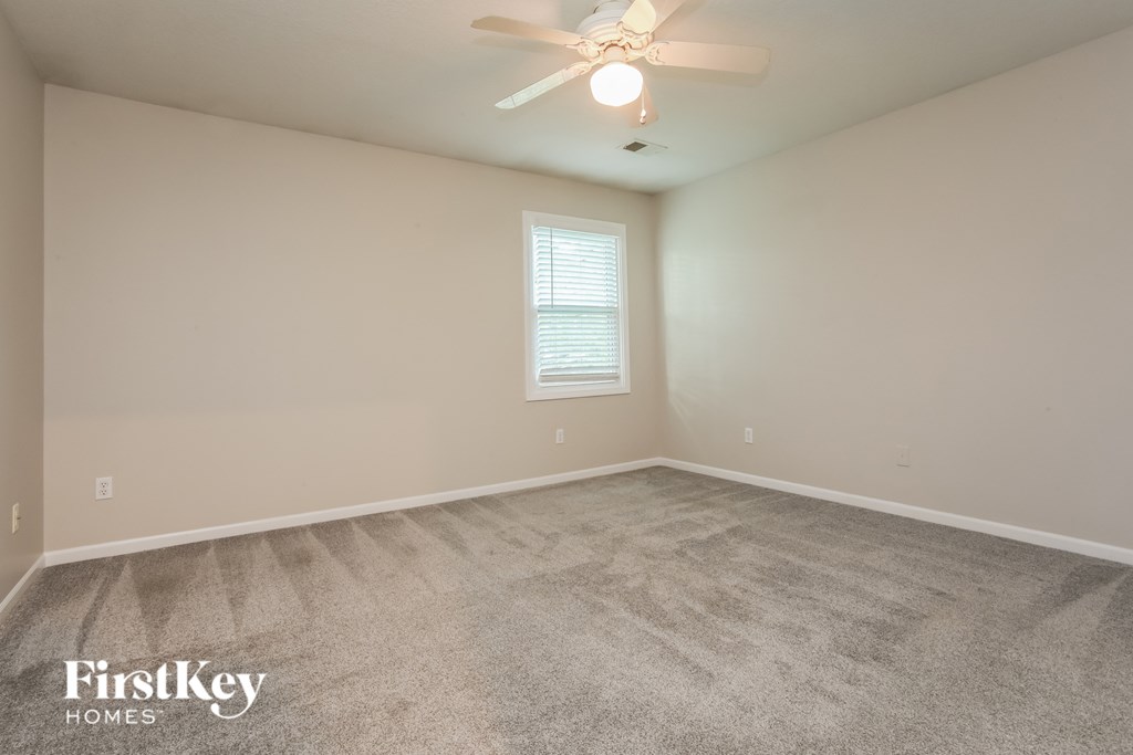 the spacious living room with carpeted flooring and a ceiling fan