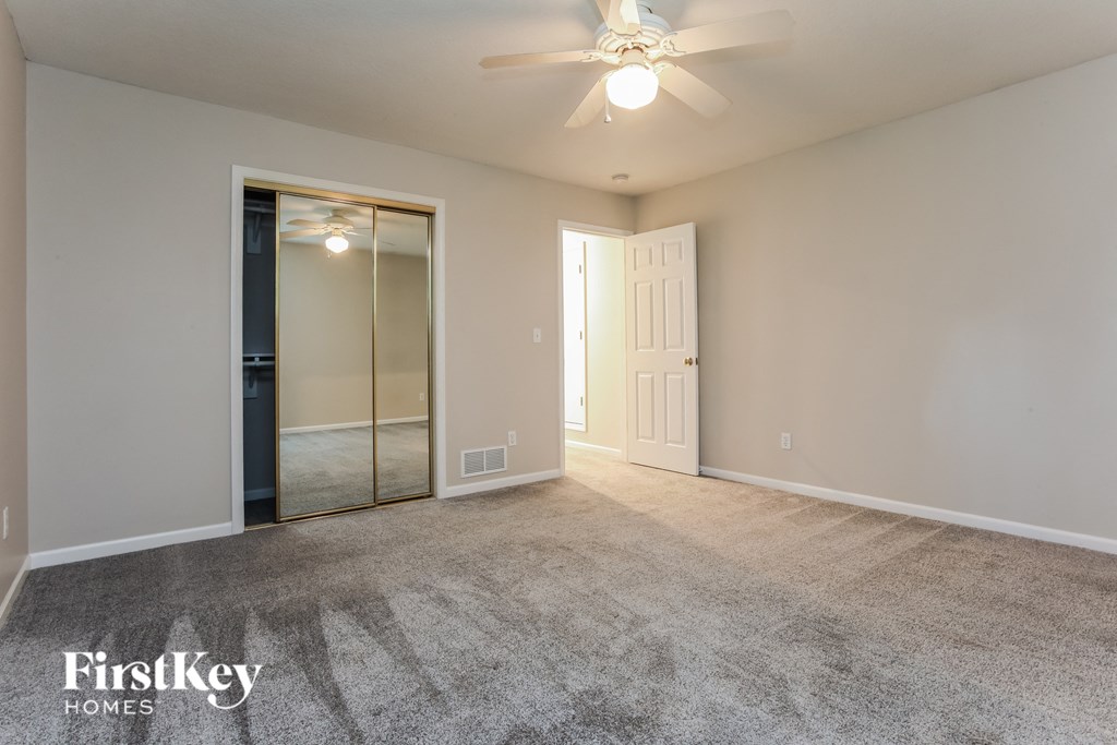 a spacious living room with carpet and a ceiling fan