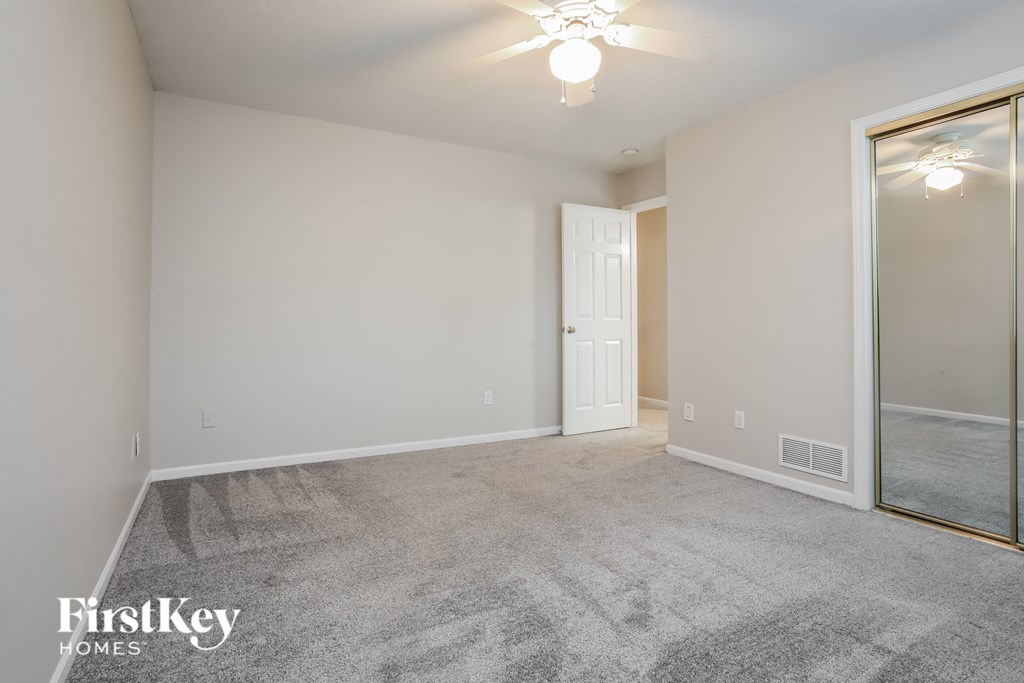 a spacious living room with carpet and a large mirror