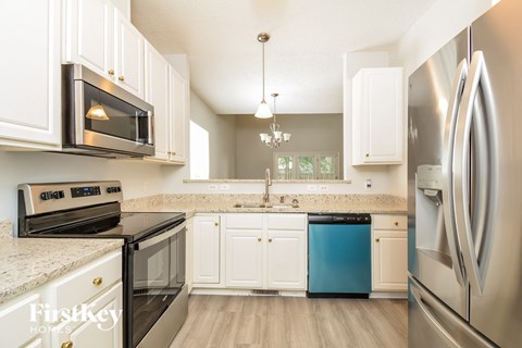 A kitchen with a black counter top and white cabinets.