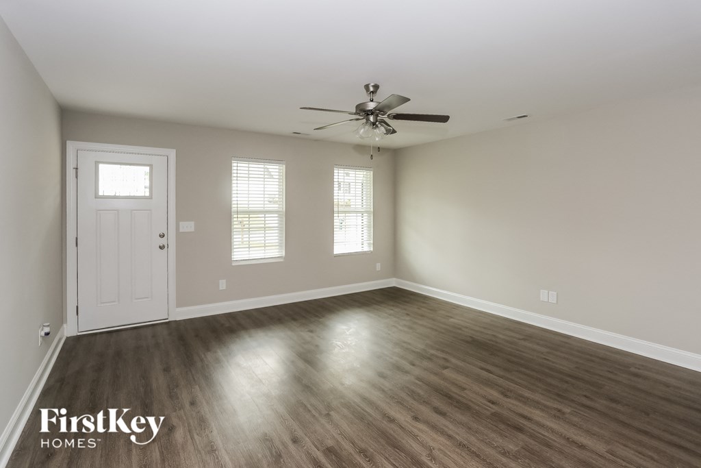 the living room of an empty house with a ceiling fan