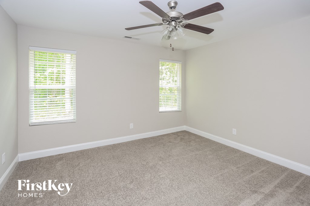 an empty room with a ceiling fan and two windows