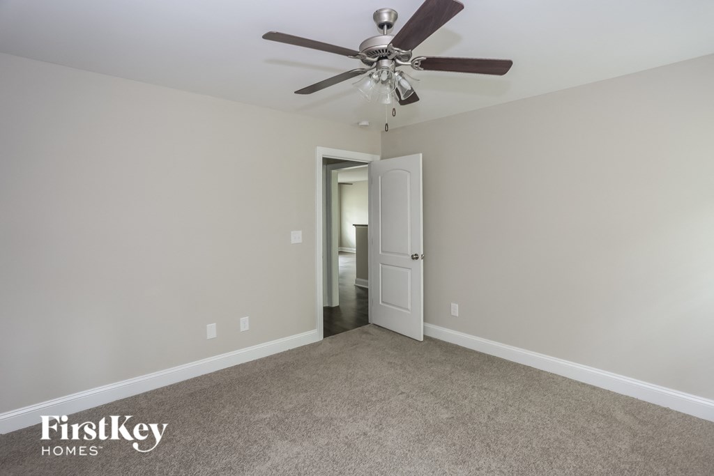 a bedroom with a ceiling fan and a door to a bathroom