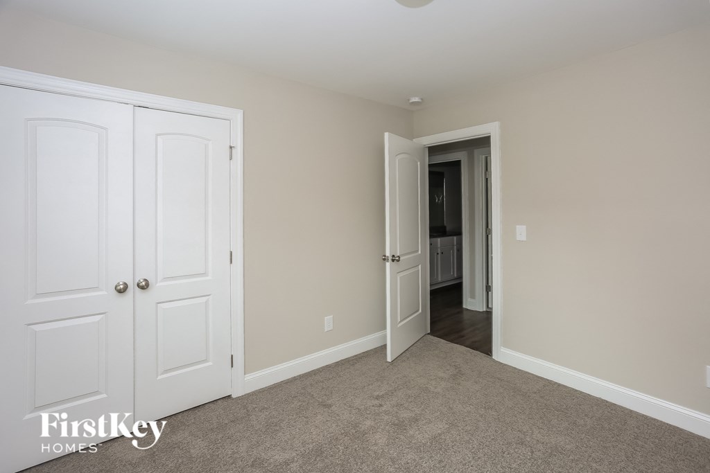 a bedroom with two closets and two doors and a carpeted floor