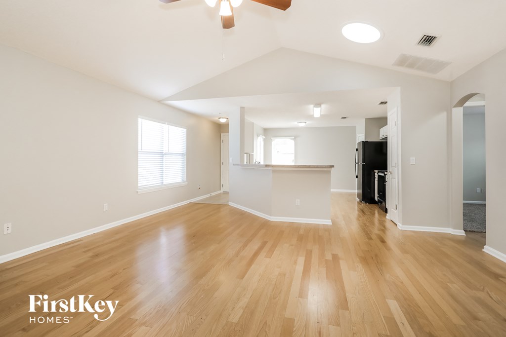 A spacious room with wooden floors and a ceiling fan.