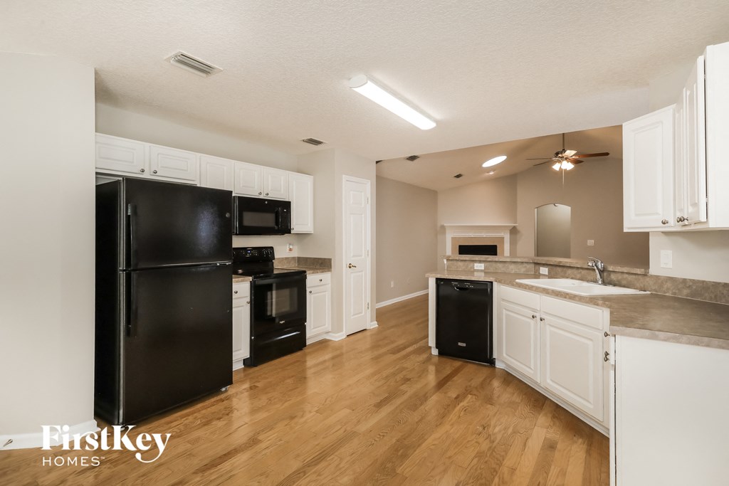 A kitchen with black appliances and white cabinets.