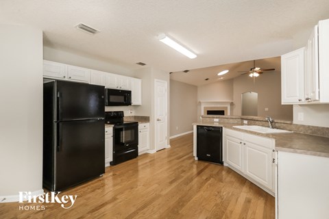 A kitchen with black appliances and white cabinets.