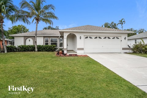 A house with a white garage door and a palm tree in front.