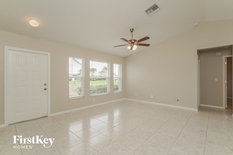 A spacious room with a ceiling fan and a door leading to another room.