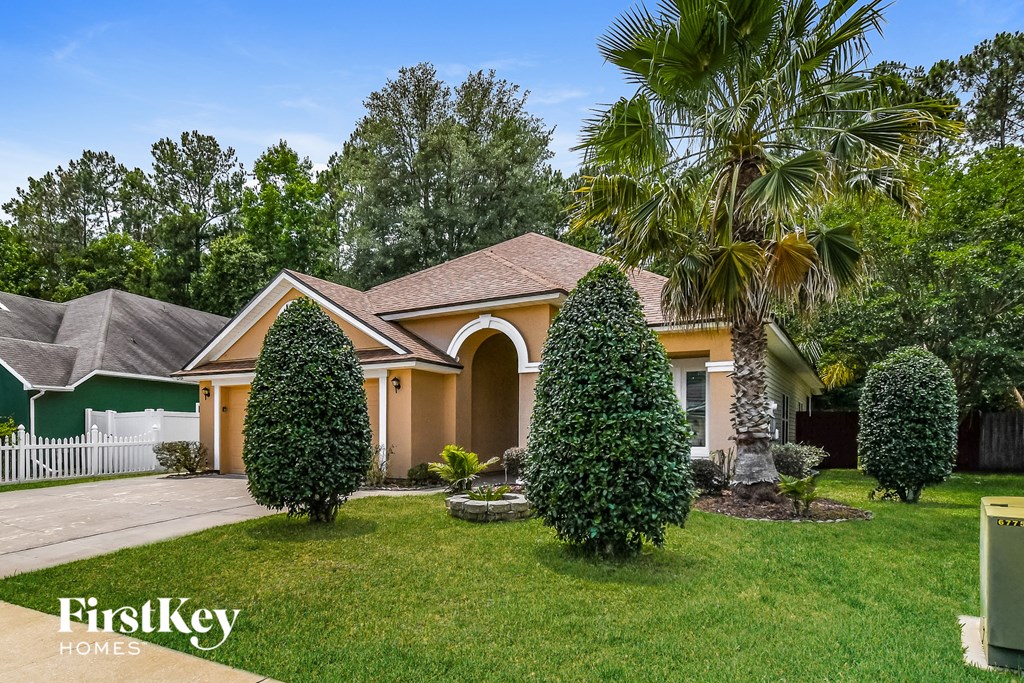 A house with a green lawn and a palm tree in front.