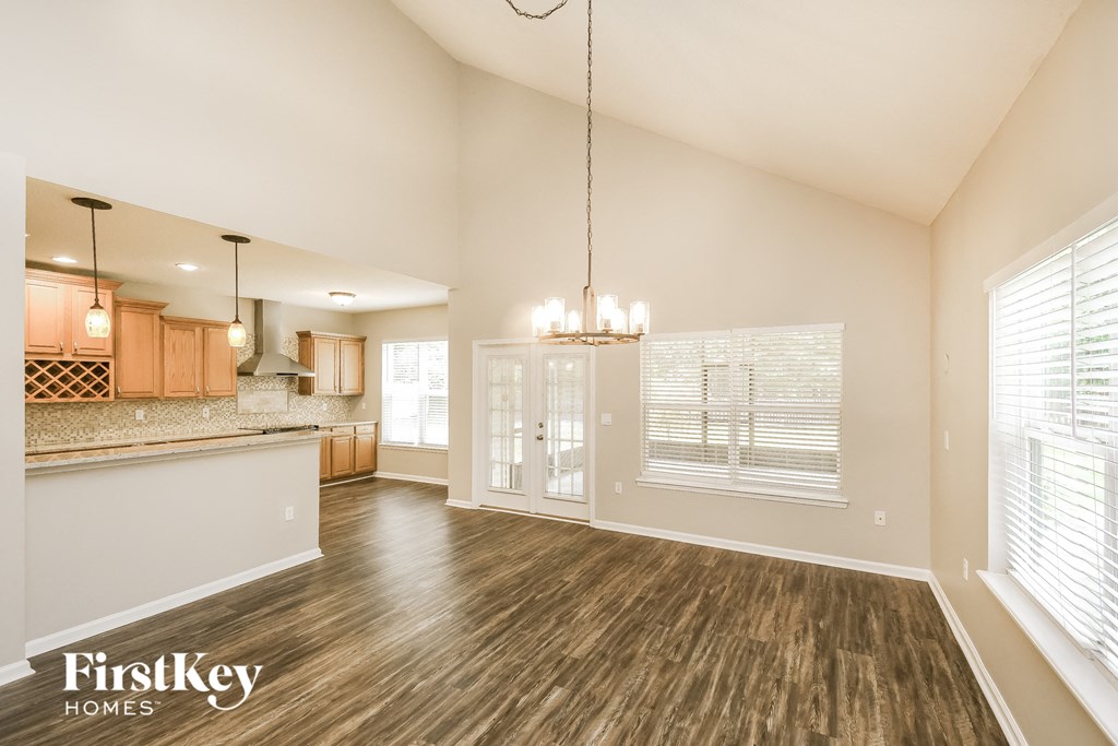 A spacious room with wooden floors and a chandelier hanging from the ceiling.